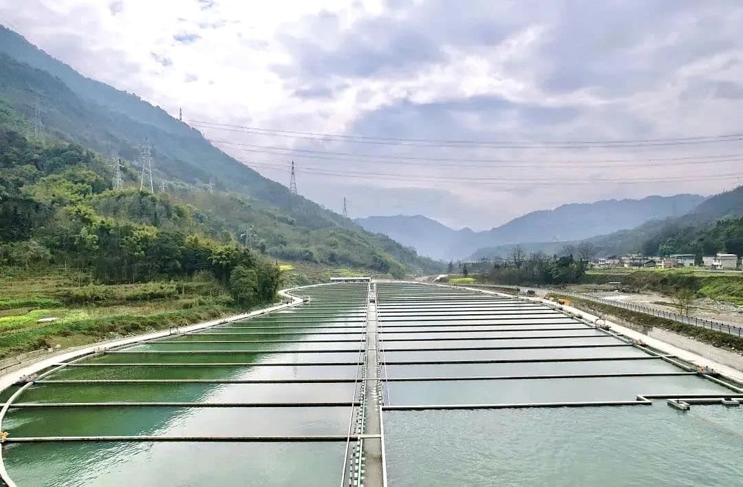 Rows of raceways running along a green river valley